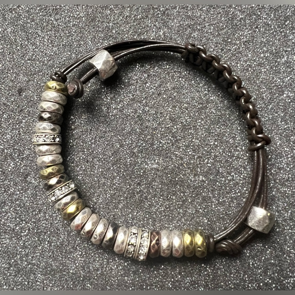 Adjustable leather strap bracelet with metal loops and rhinestone jeweled disc.